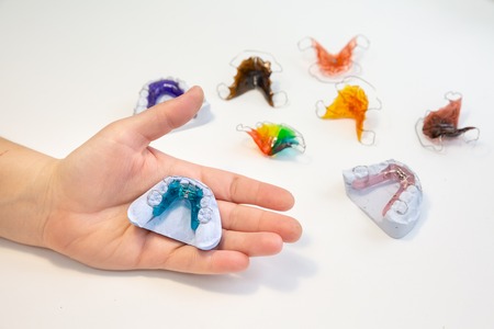 Colorful orthodontic appliances hands on white background on the casts