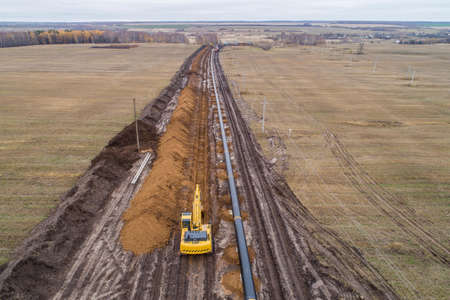 laying the pipeline with an excavator. Autumn, shooting from a drone. Earthworks, infrastructure constructionの写真素材