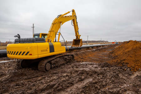 laying the pipeline with an excavator. Autumn, shooting from a drone. Earthworks, infrastructure constructionの写真素材