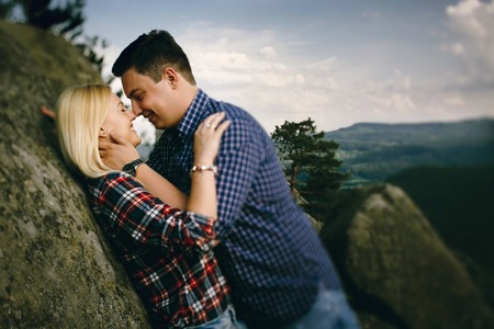Young beautiful couple in jeans and shirts for a walk in the mountains. Romantic kiss couple in love.の写真素材