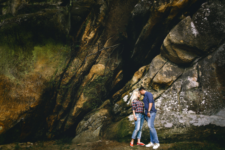 Young beautiful couple in jeans and shirts for a walk in the mountains. Romantic kiss couple in love.の写真素材