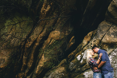 Young beautiful couple in jeans and shirts for a walk in the mountains. Romantic kiss couple in love.の写真素材