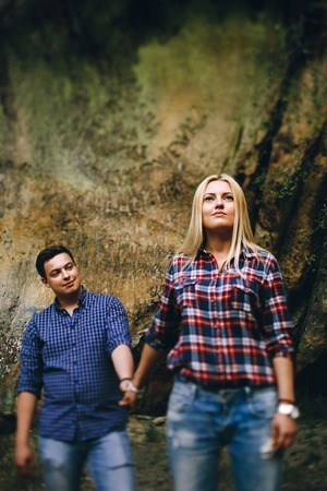 Young beautiful couple in jeans and shirts for a walk in the mountains. Romantic kiss couple in love.の写真素材