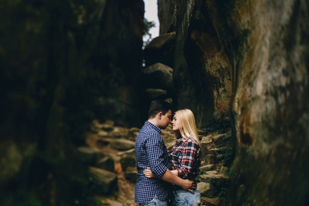 Young beautiful couple in jeans and shirts for a walk in the mountains. Romantic kissの写真素材