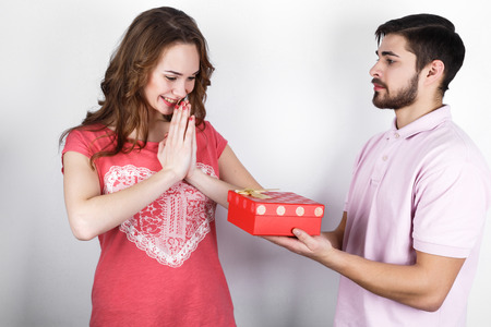 Young handsome  dark-haired guy gives his sweetheart  gift in the box for Valentine's Day or birthdayの写真素材