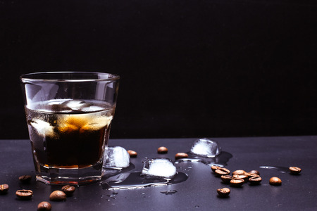 Tasty ice coffee with coffee beans on the tableの写真素材
