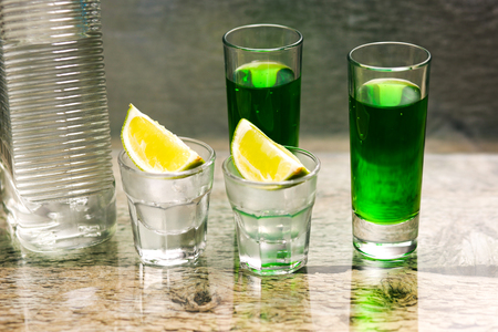 Vodka with lemon, bottle and green liquorの写真素材