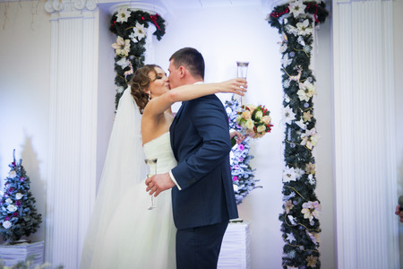 Cheerful newlywed couple kissing drinking champagne at receptionの写真素材