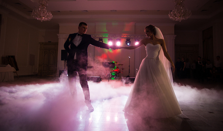 Beautiful newlywed couple first dance at reception, smoke surrondingsの写真素材