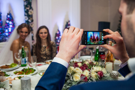 Groom taking picture of happy bride bridesmaid at receptionの写真素材