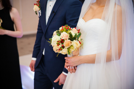 Stylish newlywed couple with bouquet at wedding receptionの写真素材