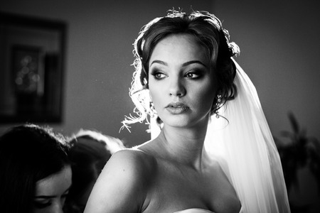 Bridesmaids helping gorgeous bride prepare for wedding closeup bwの写真素材