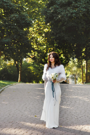 Bride walks with a lily bouqet in the parkの写真素材