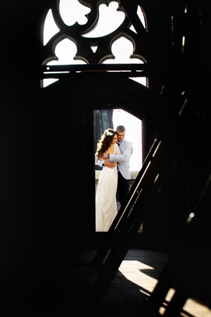 Bride and fiance hug in the door to rooftop of Gothic cathedralの写真素材