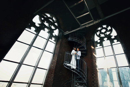 Bride and fiance standing on the spiral stairs in old Gothic cathedralの写真素材