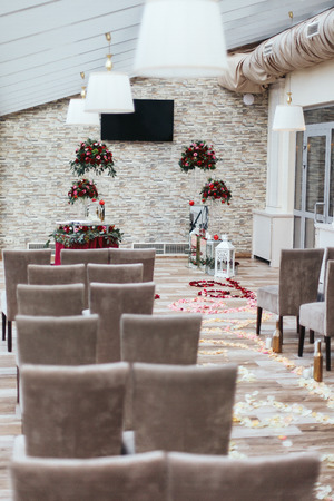 Aisle in the hall decorated with white petals and red bouquetsの写真素材