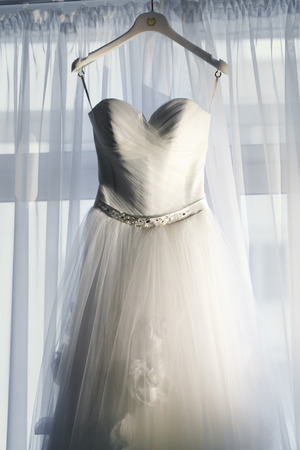 Wedding dress on the hanger before the windowの写真素材