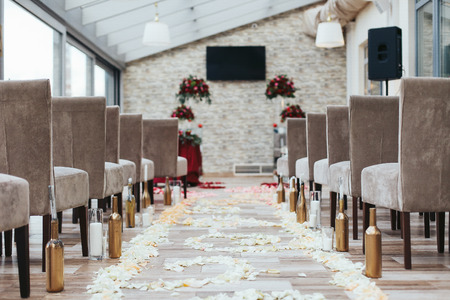 Aisle in the hall between brown chairs with white petals on the floorの写真素材
