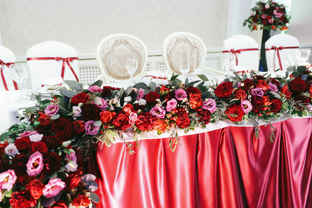 Roses, ranunculus, peonies and greenery wreathed in the bunch on the wedding tableの写真素材