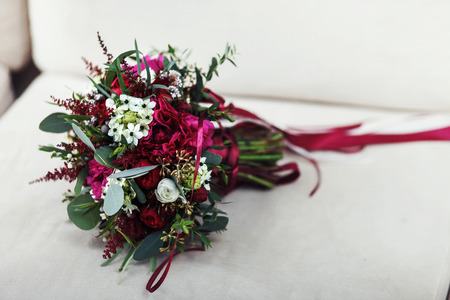 Wedding bouquet of roses, ranunculus and peony lies on a white chairの写真素材