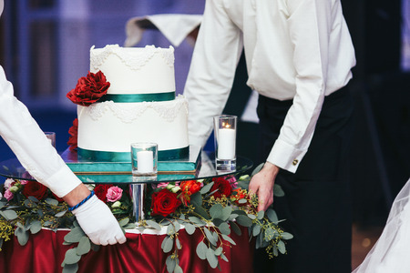 Waiter bring a white wedding cake on the decorated tableの写真素材