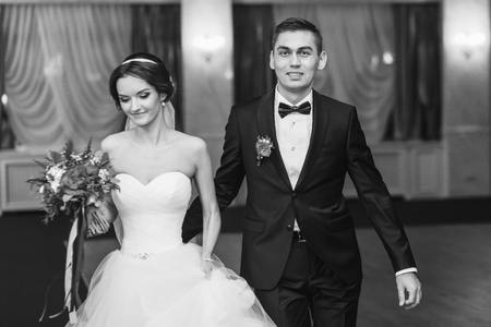 Fiance smiles to the camera while leading bride to the first danceの写真素材