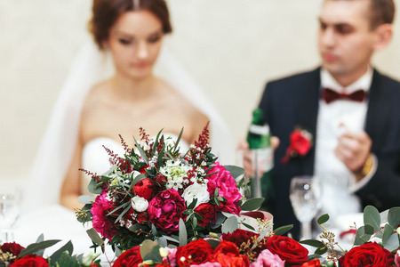 Bouquet of peonies, ranunculus and roses stand in the front of just marriedの写真素材