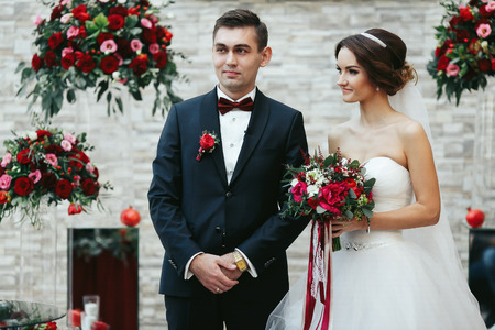 Bride and bridegroom stand smiling during the engagement ceremonyの写真素材