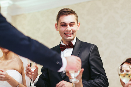 Fiance smiles while drinking to the guestsの写真素材