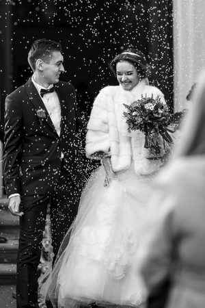 Newlyweds smile in the rain of rice  in the front of the churchの写真素材