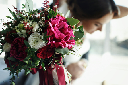 Bride reach out a hand with bouquet decorated with red and white flowersの写真素材