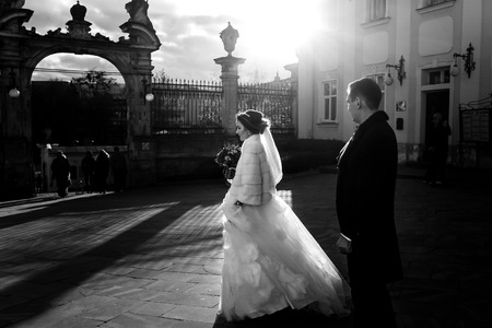 Bride goes towards the church gates in the rays of sunlightの写真素材