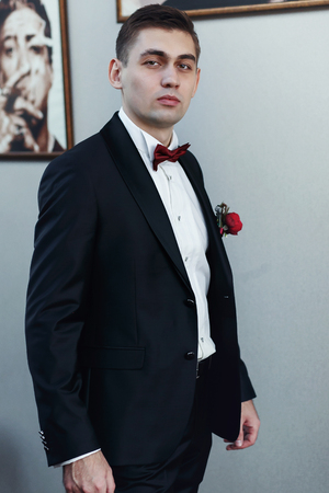 Confident young man in tuxedo with bow tie posing at cameraの写真素材