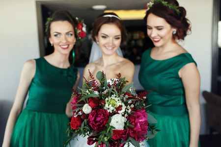 Bride surrounded by braidsmaids reach out her hand with bouquetの写真素材
