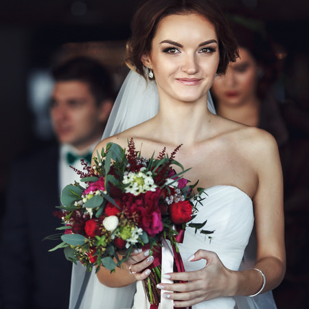 Smiling bride holds a red bouquetの写真素材