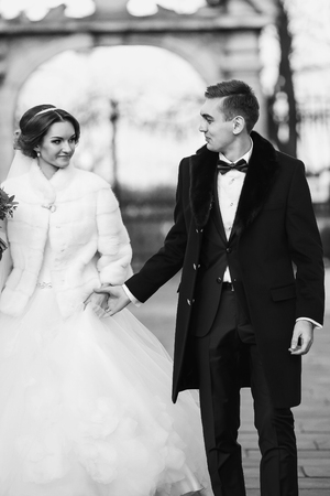 Bridegroom holds bride's hand during the walk in the parkの写真素材