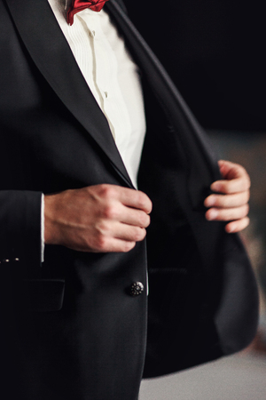 Man with red bow tie buttons up his black blazerの写真素材