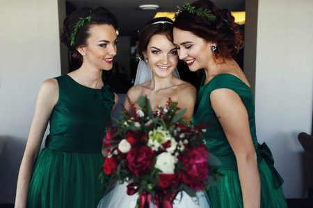 Bride reach out a bouquet while making fun with bridesmaidsの写真素材