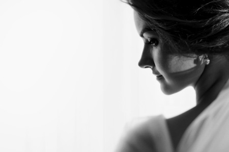 Bride looks over her shoulder in the light of the windowの写真素材
