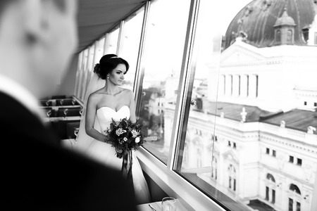 Bride looks thoughtful out of the window at cityscapeの写真素材