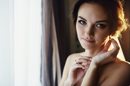 Bride posing in the lights of rising sun with hands at her faceの写真素材