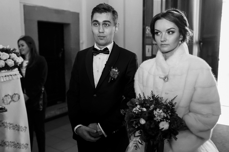 Bride and bridegroom wait thoughtfully before the ceremony in churchの写真素材