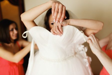 Bride puts on a weding dress with bridesmaids' helpの写真素材