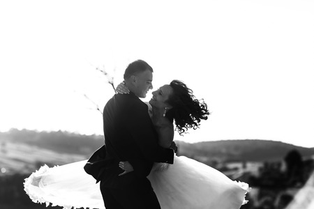 Newlyweds look at each other with love while whirling somewhere on the fieldの写真素材