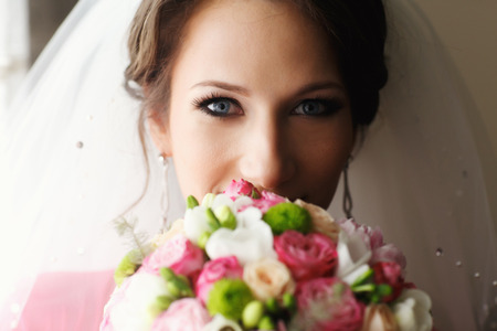 Bride with blue eyes looks above the bouquetの写真素材