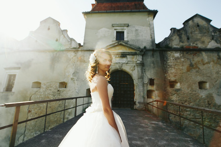 A halo of sunlight around the bride standing in the front of old castle gatesの写真素材