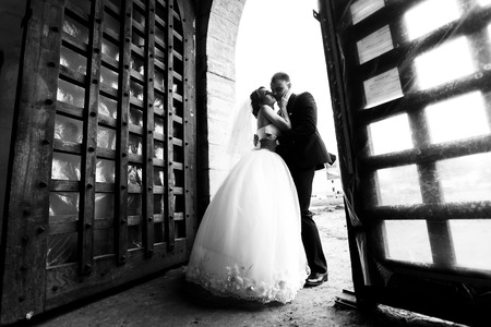 Bride kisses fiance's cheek standing in the open gatesの写真素材