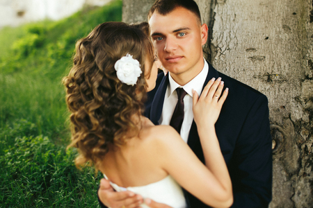 Blue-eyed groom looks thoughtful holding bride in his hugsの写真素材