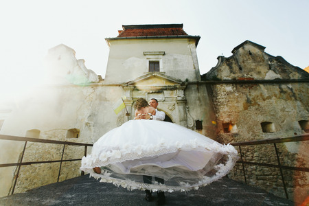 Man whirls a woman in wedding dress on the bridge to ab old castleの写真素材