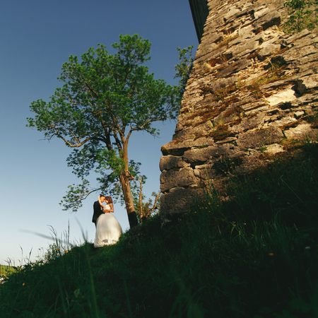 Just married stand behind a stone castle wallの写真素材